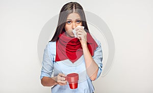 Sickness woman holding red cup blow up nose in paper tissue.