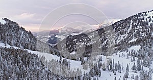 Side aerial to snowy valley with woods forest at Sella pass.Sunset or sunrise,cloudy sky.Winter Dolomites Italian Alps