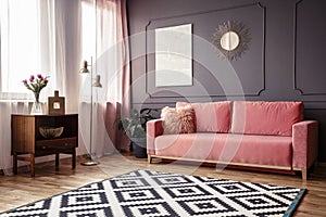 Side angle of a living room interior with a powder pink sofa, pa