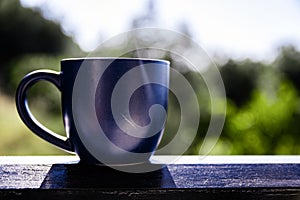 Side Angle View Of Blue Mug Of Morning Coffee Ready To Drink Against Bright Sky