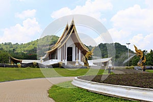 Side angle of the white Buddhist temple with dragon fountains and a pathway at Ban Nong