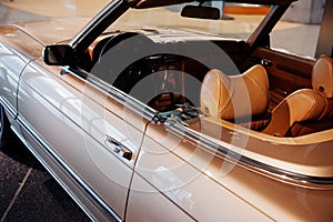Side and back, close up view of beige retro cabriolet car leather interior and hood: steering wheel, dashboard, rear