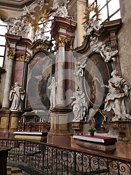 Side baroque altar with decorative religious columns, statues and paintings in Church Of Saint Peter and Paul