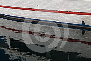 Side of a boat with its reflection in the water