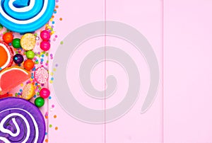 Side border of assorted colorful candies against pink wood