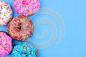 Side border of assorted donuts with pastel icing against a blue background