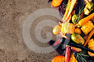 Side border of colorful roasted autumn vegetables on a rustic baking tray background