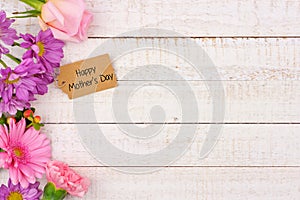 Side border of flowers with Mothers Day gift tag against white wood