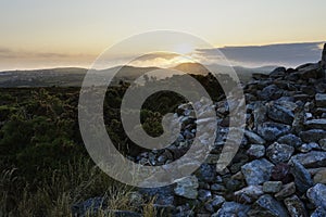 At the side of the cairn on Llanbedrog Headland as the sun sets over Snowdonia