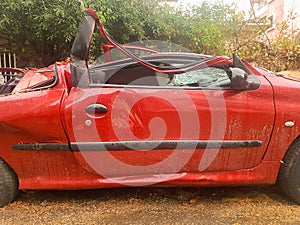 Side of a destroyed car by a tree after storm.