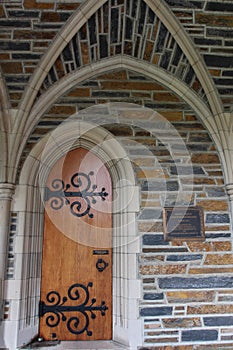 A side entryway to the Duke University Chapel, with an arched doorway, arched passageway and arched wood door