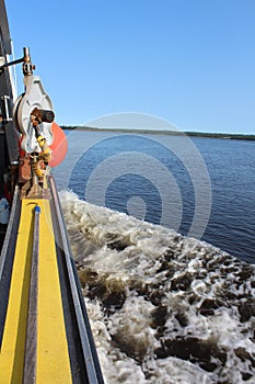 The side of a fishing boat with a gaffe with a hauling pulley and a buoy visible on a bright sunny day