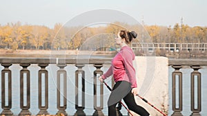 Side follow shot of chubby girl doing nordic walking in city in the morning before work. Nordic walking concept