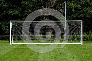 Side of football of soccer goal post with net in focus. Field out of focus. Sport background and equipment. Front view