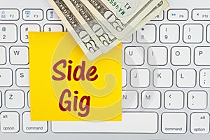 Side gig message with money on a keyboard with sticky note photo