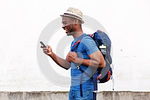 Side of happy african american tourist man holding mobile phone