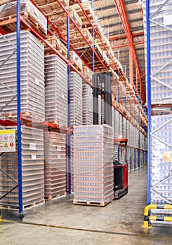 Side lift stacker operating inside large distribution warehouse with racking system