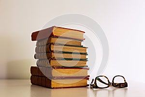 Side lit stack of old books isolated on shiny cream background