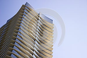 Side low angle view of a modern corporate high-rise office building with yellowish overhangs in each floor. photo