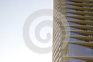 Side low angle view of a modern corporate office building with yellowish overhangs in each floor.