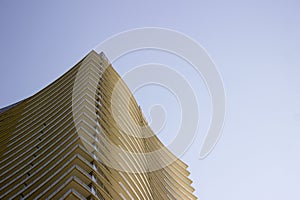 Side low angle view of the top part of a modern corporate building with yellowish overhangs in each floor.