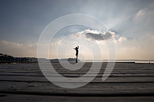 Side low angle view of a woman with arms outspread against cloud photo
