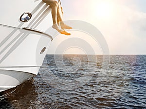 Side of luxury yacht with couple legs sunbathing in sunshine