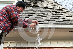 Side on of man hanging Christmas lights