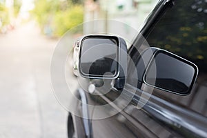Side mirror of black car on  blurred background