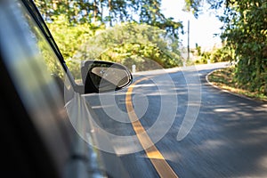 The side mirror of the car while the car ran into the curve of mountain