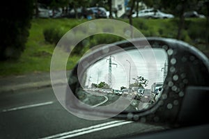 A side mirror of a car in rainy weather and traffic jams.