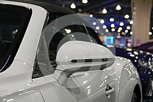 A side mirror of a pearl white color of a convertible car