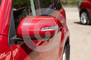 Side mirror of a red car close-up.