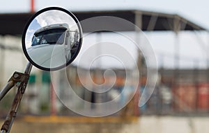 Side mirror of the truck with the reflection of the cab on the blurred background of the warehouse area