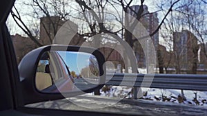 Side mirror view of red car driving on urban highway