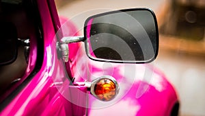 Side mirror and window of pink vintage car