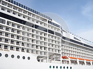 The side of a multi-deck cruise liner. Side view on sky background