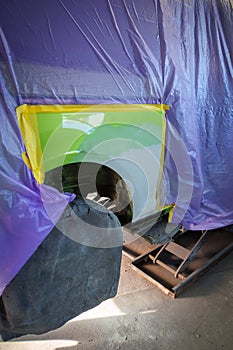 A side panel of a car is painted green in a paint shop