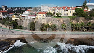 Side panning of people on Cascais to Estoril promenade with waves crashing