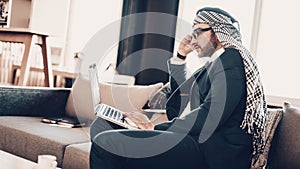Side photo of Arab looking in Laptop on couch