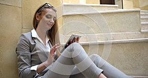 Side portrait of the attractive blonde businesswoman is happily answering the messsage via the tablet and then she is