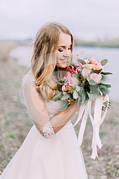 Side portrait of the bride smelling the wedding bouquet. The beach location.