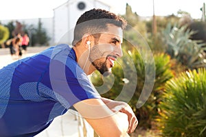 Fit young man smiling and listening to music with earphones