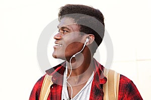 Side portrait of happy young man with earphones looking away and smiling