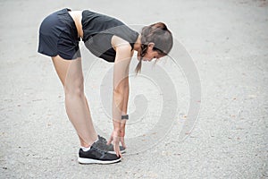 Side portrait of runner woman doing stretching and warming up her legs before running.