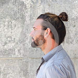 Side portrait of serious man with beard and hair bun