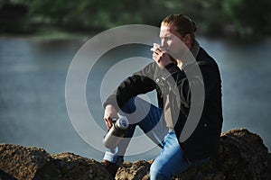 Side portrait of stylish lamber man holding thermos with hot drink , drinking tea and looking into distance enjoying nature, calm photo