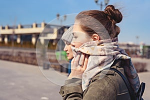 Side portrait of two young girls in a coat, scarf and hat, cold wind