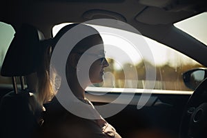 Side portrait of woman driving. Wearing sunglasses.