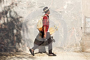 Side portrait of young african american man walking outside with skateboard